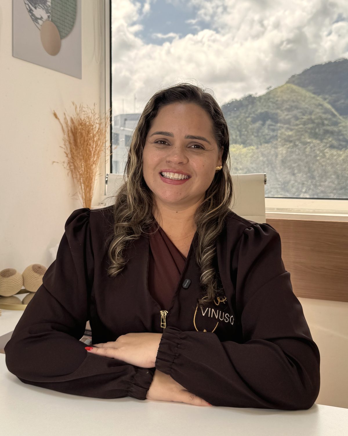 Carolina Vinuso sorrindo em seu consultório, com o uniforme da Vinuso